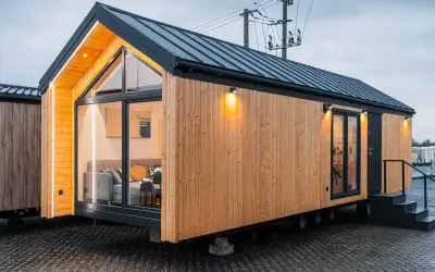 Nowoczesne domy z kontenerów, projekty i ceny. Drewniana elewacja, duże okna i oświetlenie tworzą przytulną atmosferę.