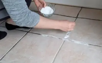 Application d'une pâte de bicarbonate et vinaigre pour nettoyer joint salle de bain.