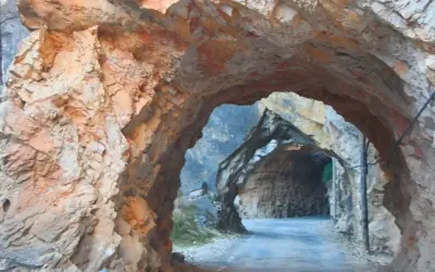 Un túnel natural en la ruta del silencio Teruel, con paredes de roca rojiza y un camino que se adentra en la montaña.