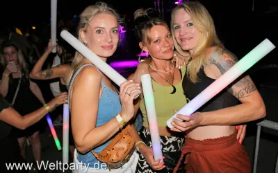 Drei Frauen mit leuchtenden Stäben auf einer Veranstaltung in Herrieden.