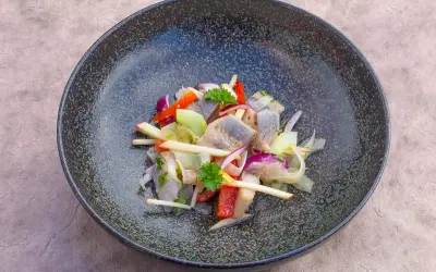 Heringssalat Hausfrauenart: ein deftiger Salat mit Hering, Apfel, Zwiebeln und Paprika in einer dunklen Schüssel.