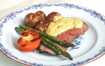 En tallrik med ryggbiff, potatis, sparris och tomat. En krämig sås toppar köttet. Ett perfekt ryggbiff recept!