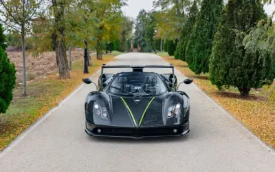 Czarny Pagani Zonda z zielonym akcentem na masce, zaparkowany na alei. Jego cena jest astronomiczna.