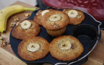 Frisch gebackene Bananen Nuss Muffins, garniert mit Bananenscheiben und Walnüssen, liegen in einer Muffinform.
