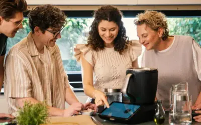 Pięć osób przygląda się ekranowi urządzenia kuchennego, szukając inspiracji na thermomix top 10 przepisów.