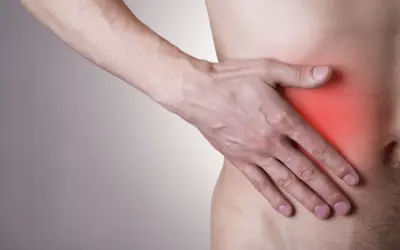 Mężczyzna trzyma rękę na boku, gdzie czerwony obszar sugeruje, że boli wątroba.