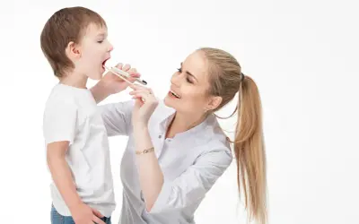Lekarka bada gardło chłopca, używając patyczka do oceny języczka podniebiennego.