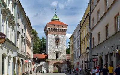 Brama Floriańska w Krakowie, majestatyczna wieża z czerwoną dachówką i kamienną fasadą, wita spacerowiczów.