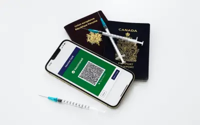 Gotowi na podróż? Paszporty, telefon z potwierdzeniem szczepień i strzykawki symbolizują przygotowania do wyjazdu.