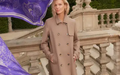 Elegancka kobieta w beżowym płaszczu, obok niej powiewa fioletowy szal z wzorem. Zastanawiasz się, jaki kolor pasuje do fioletu? Beż jest doskonałym wyborem!