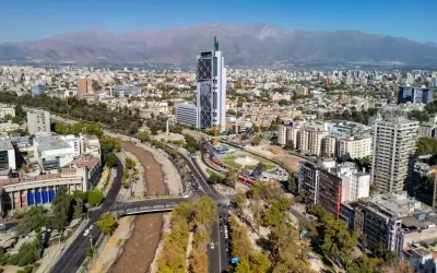 Widok na nowoczesną architekturę i rzekę w Santiago, stolicy Chile, z górami w tle.