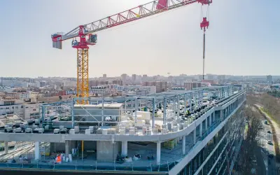Grue de chantier sur un bâtiment en construction rapide, avec une ville en arrière-plan.