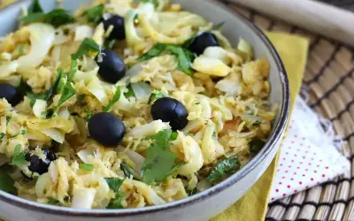 Un plat de bacalhau à bras, mélange savoureux de morue effilochée, d'oignons, d'œufs brouillés et d'olives noires, garni de persil frais.