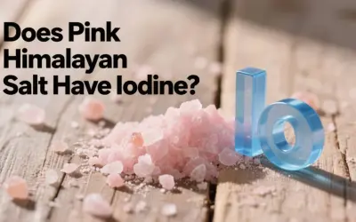 Góra różowej soli himalajskiej na drewnianym blacie, obok niebieskie litery "I" i "O", sugerujące pytanie: czy sól himalajska jest jodowana?