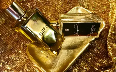 Dwa flakony perfum Marc Antoine Barrois na złotej, cekinowej tkaninie. Jeden flakon z napisem B683, drugi z nazwą "Ganymede".