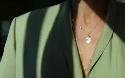 Delikatna biżuteria z pereł i okrągłą zawieszką na zielonej marynarce. Idealny dodatek do styl casual.