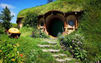 Zielone drzwi i okrągłe okna w zboczu wzgórza, gdzie mieszkał Bilbo Baggins. Obok wielka dynia na taczce.