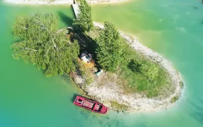 Un séjour insolite en Île-de-France : une petite île avec une cabane, un bateau rouge et un ponton.
