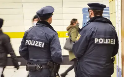 Zwei Polizisten stehen in einer U-Bahn-Station. Im Hintergrund sind 53 Personen zu sehen, die sich bewegen.