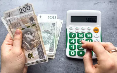 Ręka trzyma banknoty 200 zł i 100 zł, obok kalkulator z wyświetloną kwotą 50000. Czy to już minimalna krajowa?