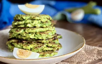 Pila di rosti di zucchine dorati, guarnita con spicchi di uovo sodo. Un piatto leggero e gustoso.