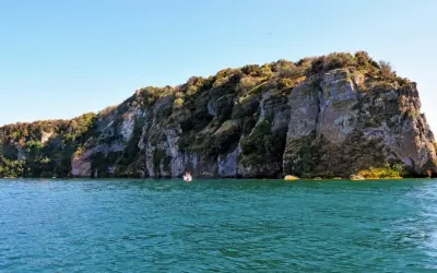 Un'emozionante visita all'isola Martana, con le sue scogliere imponenti e il mare turchese. Una piccola barca si avvicina alla costa rocciosa.