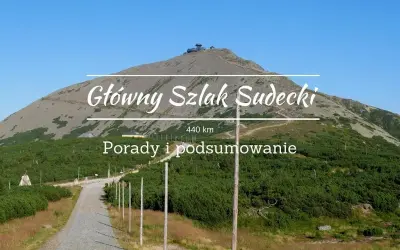 Kamienista ścieżka prowadzi na szczyt góry, gdzie widać budynek. Nad krajobrazem widnieje napis "Główny Szlak Sudecki".