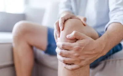 Mężczyzna trzyma się za bolące kolano, sugerując uraz kolana, który może być klasyfikowany według ICD 10.