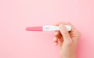 Dłoń trzyma test ciążowy z dwoma różowymi kreskami. To może być początek nowej drogi, nawet jeśli ciąża w młodym wieku niesie wyzwania.
