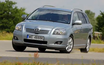 Srebrny kombi Toyota Avensis T25 z polskimi tablicami WE 4888K pokonuje zakręt na drodze, unosząc lekki pył.