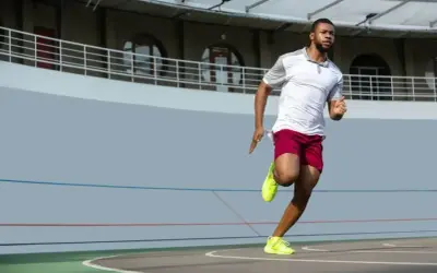 Mężczyzna w sportowym stroju biegnie po bieżni. Zastanawiasz się, jak szybko biega Usain Bolt? Ten zawodnik daje z siebie wszystko!