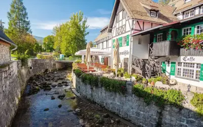 Urokliwy deptak w Szklarskiej Porębie nad górskim potokiem. Restauracja z ogródkiem i zielonymi okiennicami.