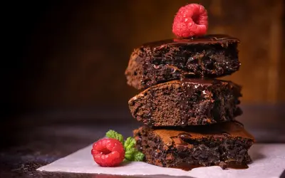 Stos pysznych, wilgotnych brownie z polewą czekoladową i malinami. Idealny brownie prosty przepis na domowe ciasto.