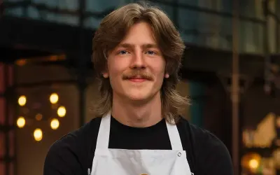 Jacob Jansson, en ung man med mustasch och långt hår, bär en vit kockförkläde.