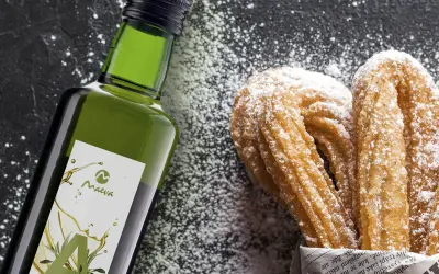 Botella de aceite de oliva junto a churros espolvoreados con azúcar glas.