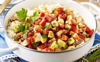 Eine köstliche zucchini-reis-pfanne einfach zubereitet mit viel Gemüse und Hähnchen. Frisch garniert mit Petersilie.
