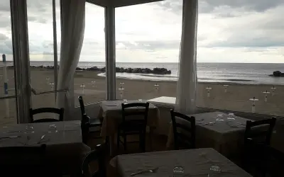 Tavoli apparecchiati in un ristorante con vista sulla spiaggia di Misano durante la bassa marea.