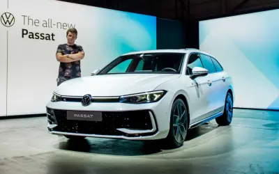Mężczyzna stoi obok białego kombi, prezentując nowy Passat 2024.