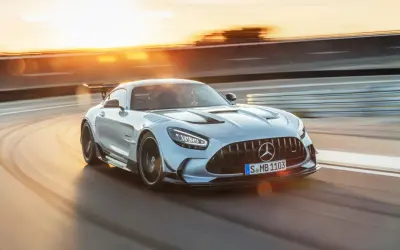 Srebrny Mercedes-AMG GT Black Series na torze wyścigowym, w promieniach zachodzącego słońca.