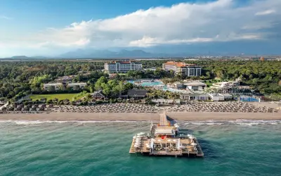 Turkusowe morze w Turcji otacza luksusowy kurort z molo, basenami i plażą pełną leżaków.