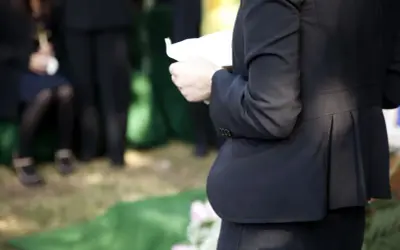 Kobieta w czerni trzyma kartkę, być może czyta panegiryk. Co to jest? To mowa pochwalna, często wygłaszana na pogrzebie.