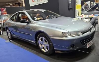Elegancki, srebrny Peugeot 406 coupe z brązową tapicerką, prezentowany na wystawie.