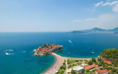 Sveti Stefan, Czarnogóra, to malownicza wyspa z czerwonymi dachami, połączona z lądem piaszczystą plażą. Czy Czarnogóra jest bezpieczna? Tak, to spokojne miejsce na wakacje.