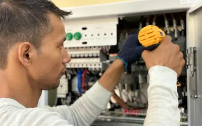 Elektryk pracuje przy panelu sterowania, unikając przeciążenia systemu.