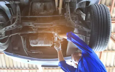 Mechanik reguluje przekładnię kierowniczą, aby usunąć luz na śrubie regulacyjnej. Naprawa zawieszenia samochodu.