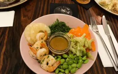 Kraków co zjeść? Kolorowa miska z krewetkami, ananasem, edamame i sosem. Idealna na lekki posiłek.