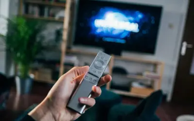 Dłoń trzyma pilota do telewizora, na ekranie logo Universal. Czas na seans filmowy z DVB-T.