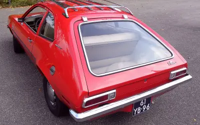 Czerwony Ford Pinto Runabout z bagażnikiem dachowym, gotowy na przygodę.