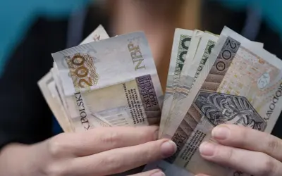 Dłonie trzymające plik banknotów 200 zł. Czy to najwyższa emerytura w Polsce?