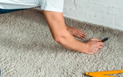 Handwerker verlegt Teppich mit einem Cuttermesser und einem Zollstock.